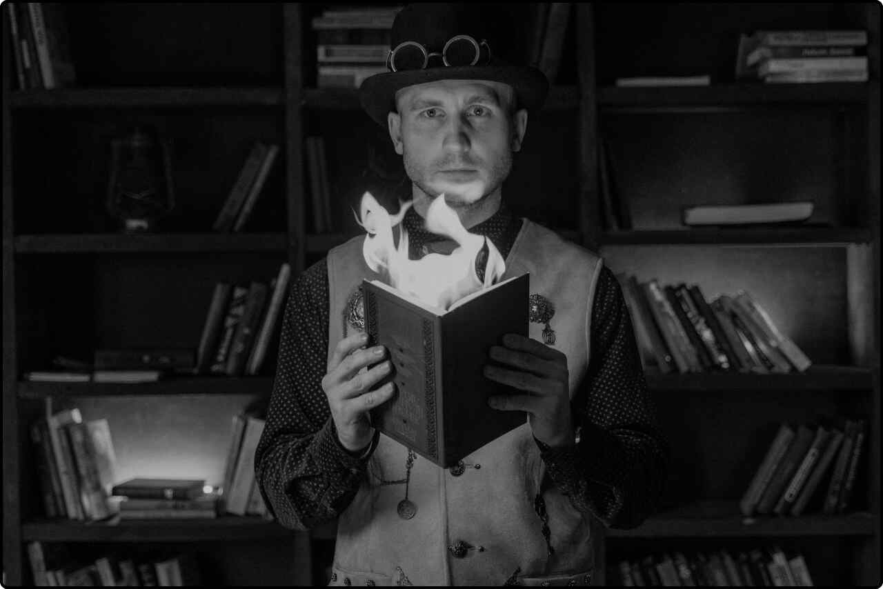 An illusionist performing with a book on fire, holding it in one hand.